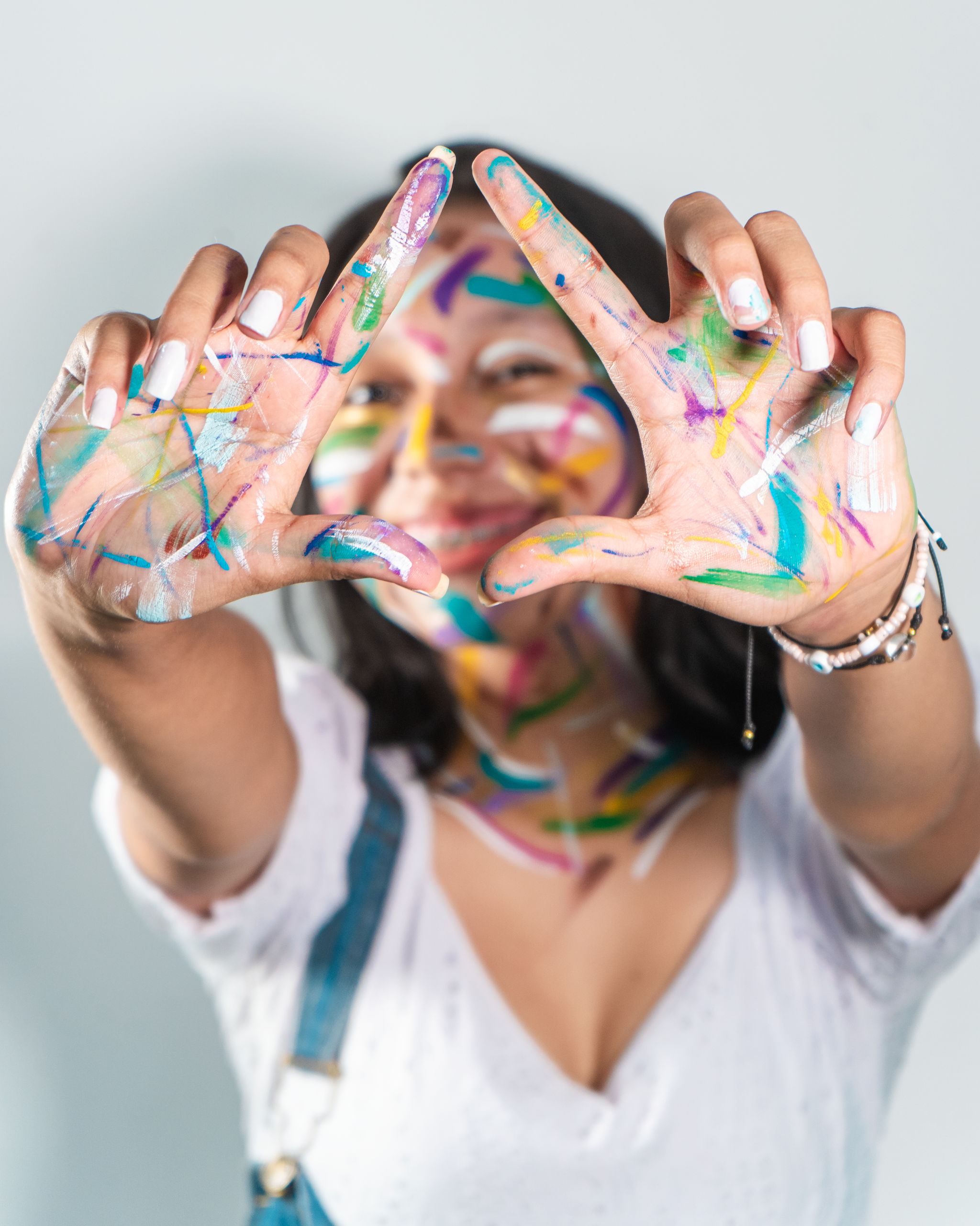 A young woman creatively expresses herself with paint on her face and hands.