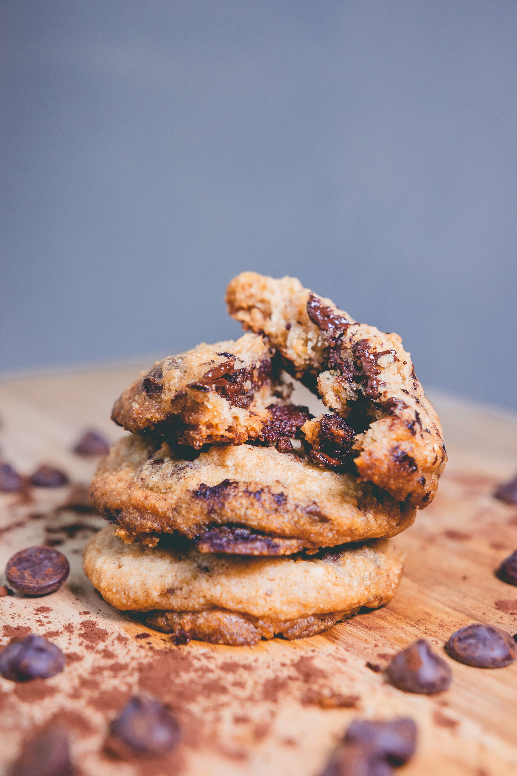 Close-up of a stack of homemade chocolate chip cookies with chocolate chips scattered around.