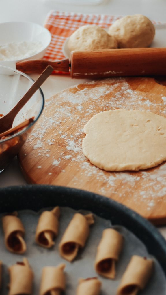 Close-up of dough preparation on a wooden board with rolling pin and baking tray.