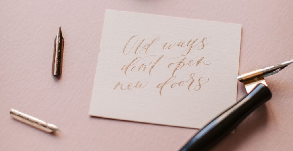 Artistic calligraphy on a note with a pen and ink, set against a pastel backdrop.